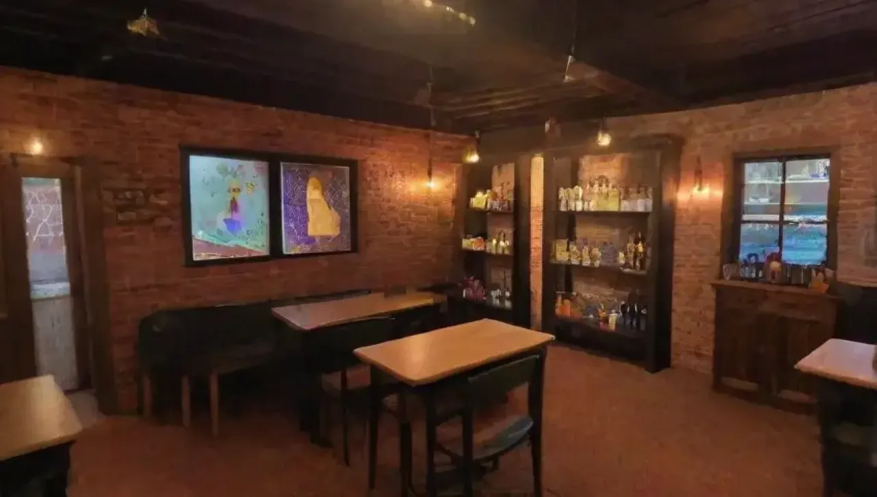 Un acogedor café con mesas de madera, luces suaves, decoración vintage y un ambiente cálido y conversador