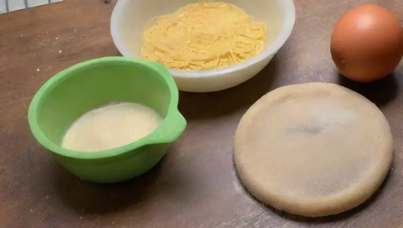 Una mesa rústica prepara pasta fresca con ingredientes vibrantes y un plato listo para disfrutar