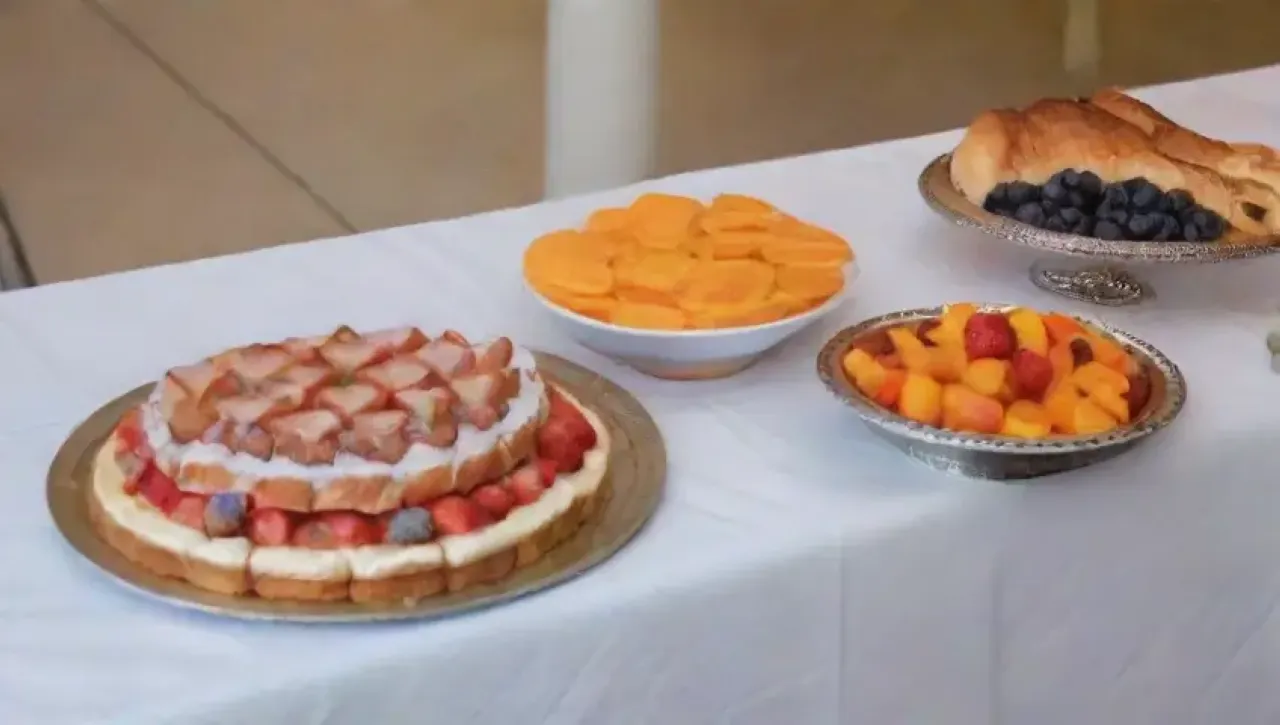 Una mesa elegantemente decorada con manteles vibrantes, cubiertos pulidos, platos coloridos y flores frescas