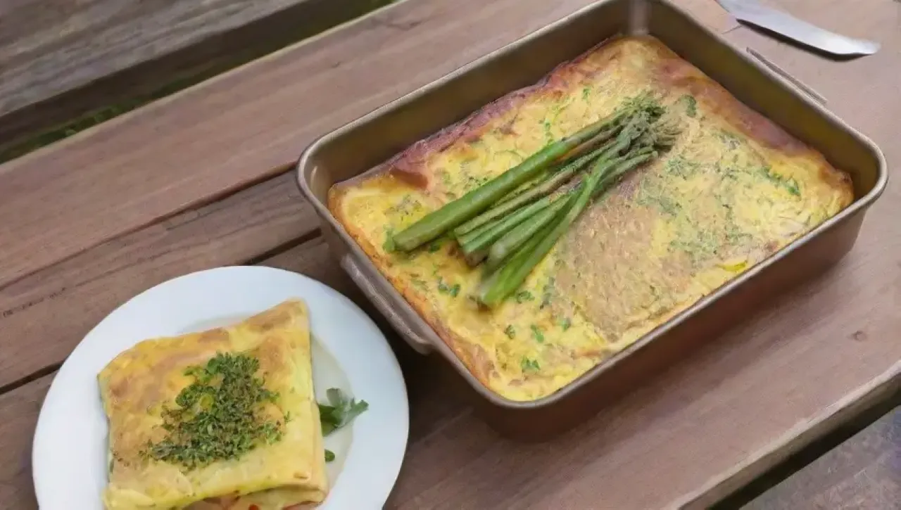 Desayuno colorido y acogedor con omelet amarillo, espárragos, jamón y hierbas frescas