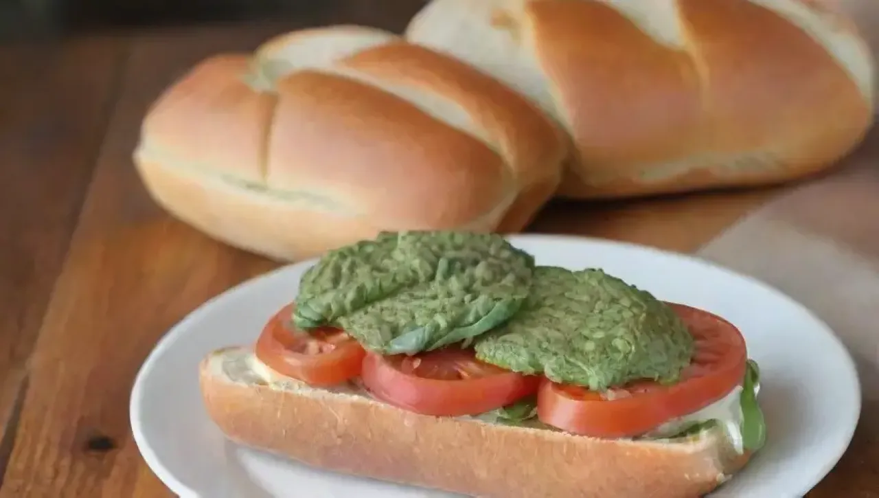 Una mesa rústica con un delicioso sándwich de ciabatta, ingredientes frescos y un ambiente acogedor