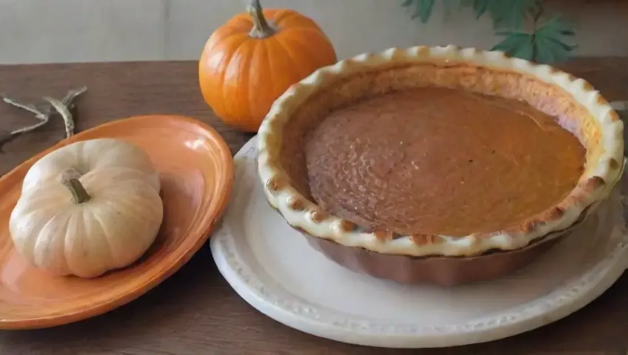 Un acogedor ambiente otoñal con calabazas, hojas doradas y luz de velas