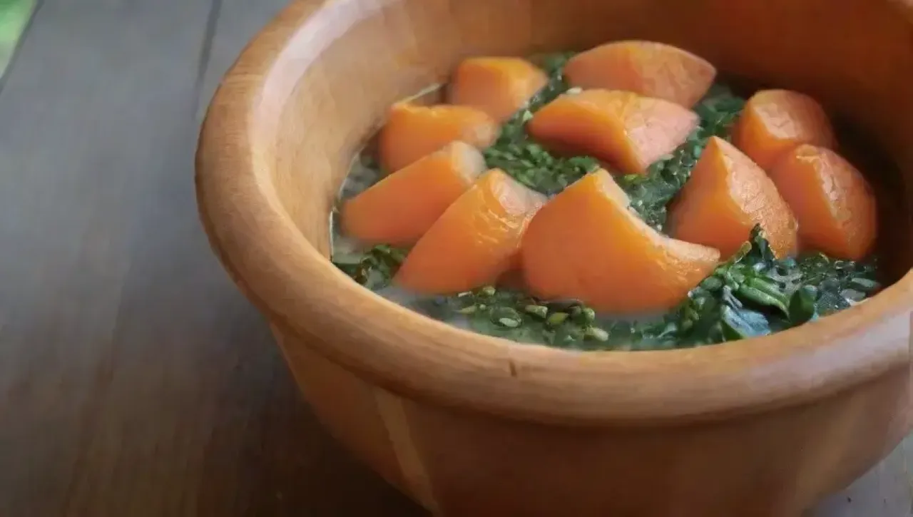 Batatas naranjas humeantes en un tazón rústico, decoradas con hierbas frescas y sal marina, evocan un ambiente acogedor de comida reconfortante