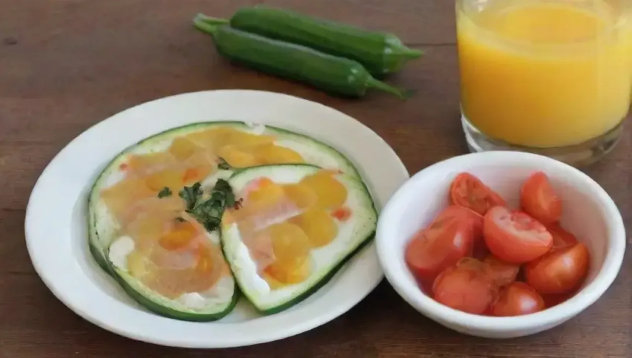 Un desayuno acogedor con calabacín, mozzarella, huevos, tomate y jugo de naranja