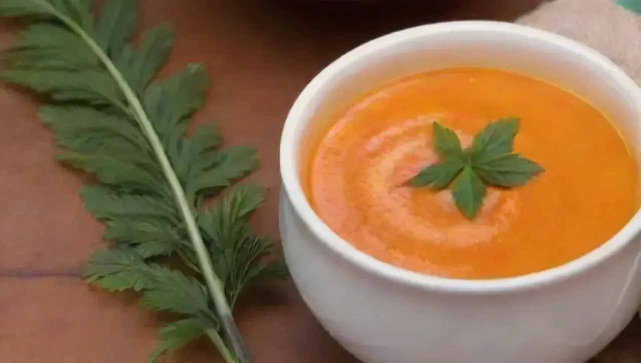 Sopa de batata naranja vibrante y cremosa, decorada con canela y hierbas, en un ambiente cálido y acogedor