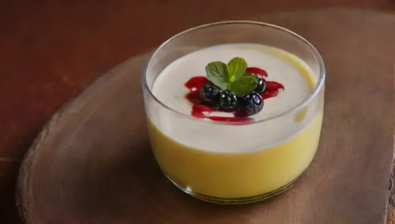 Panna cotta suave y cremosa decorada con coulis de bayas y flores comestibles en un ambiente acogedor