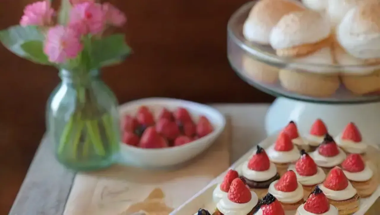 Una mesa rústica y acogedora llena de postres coloridos y elegantes