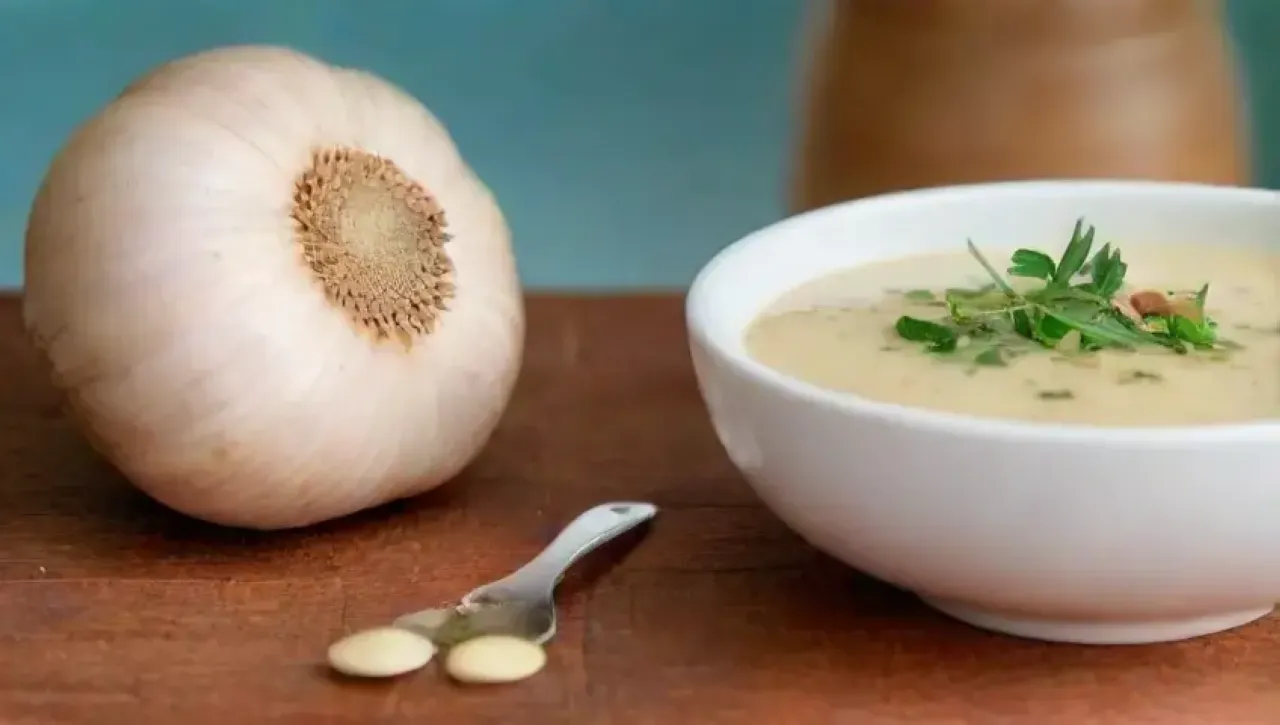 Un bulbo de ajo vibrante en una mesa rústica, rodeado de hierbas frescas y un ambiente acogedor de cocina saludable