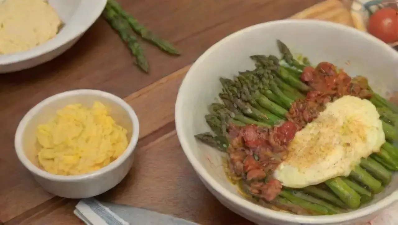 Desayuno colorido con omelet, espárragos, pan crujiente y jugo de naranja en una cocina iluminada