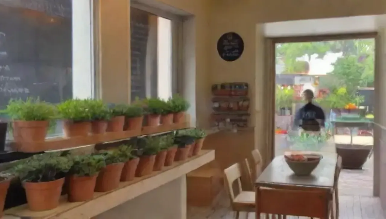 Un acogedor café lleno de luz natural, plantas, arte y aromas, donde amigos disfrutan de té y pasteles