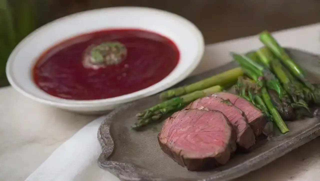Una mesa rústica con un filete mignon, vino tinto, y un ambiente acogedor
