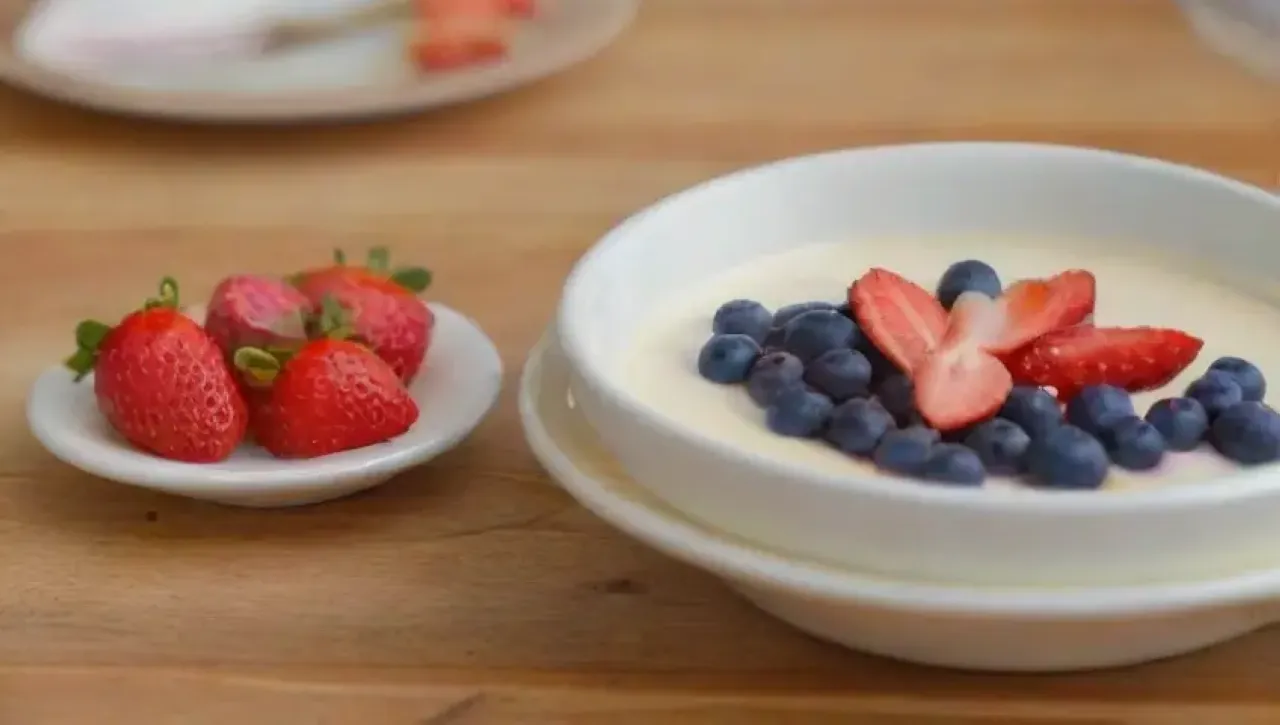 Panna cotta suave con caramelo, frutas frescas y flores comestibles en un elegante plato
