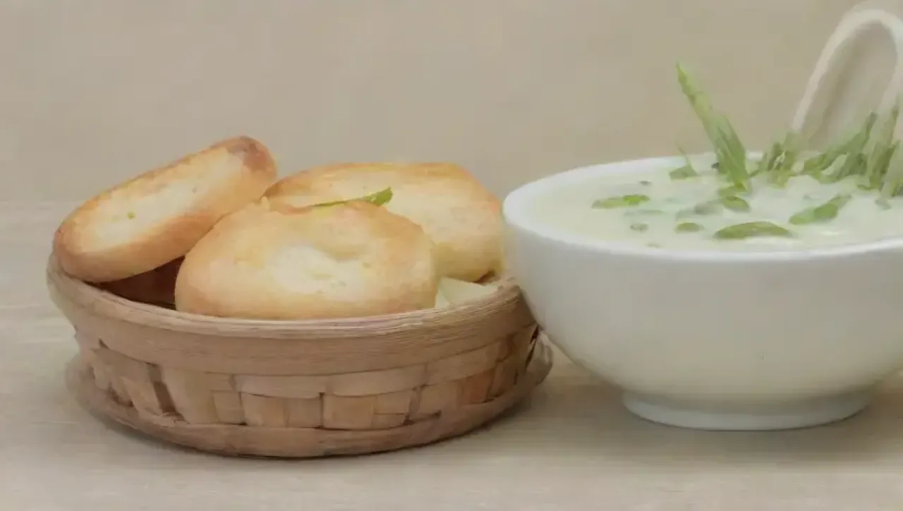 Sopa de espárragos en un elegante tazón blanco, con chives, aceite de oliva y un ambiente acogedor