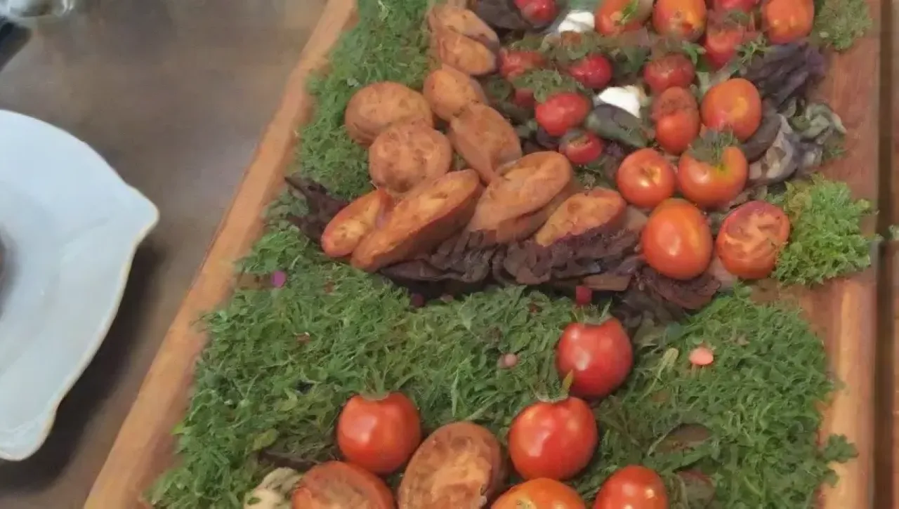 Plato de bruschetta elegante con tomates, albahaca, burrata, pan tostado y flores comestibles en un ambiente cálido