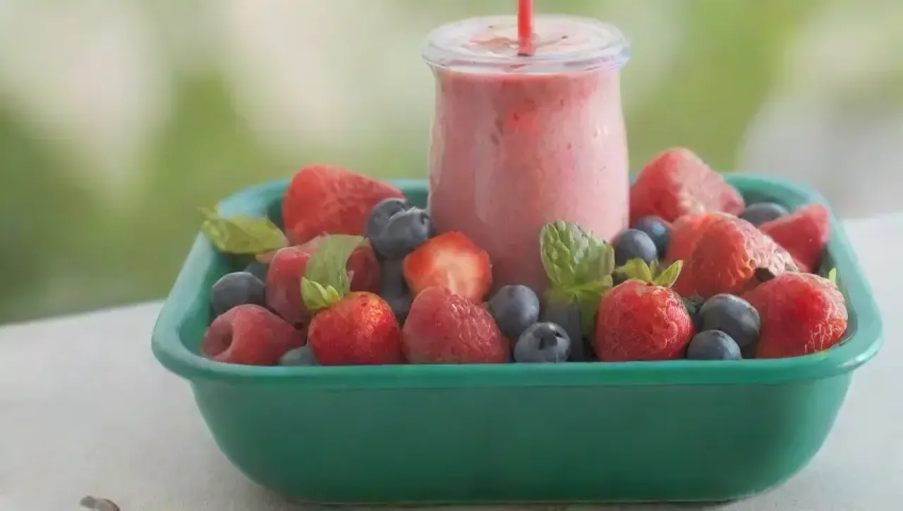 Un batido vibrante y saludable con frutas frescas y un ambiente alegre en la cocina