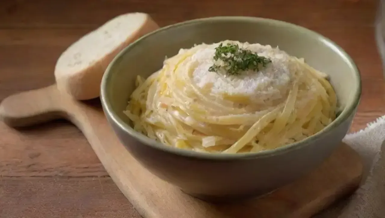 Pasta cremosa con queso, pimienta y ajo, servida en un ambiente acogedor