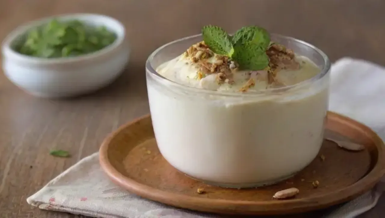 Panna cotta cremosa adornada con frutas, caramelo y pistachos, lista para disfrutar
