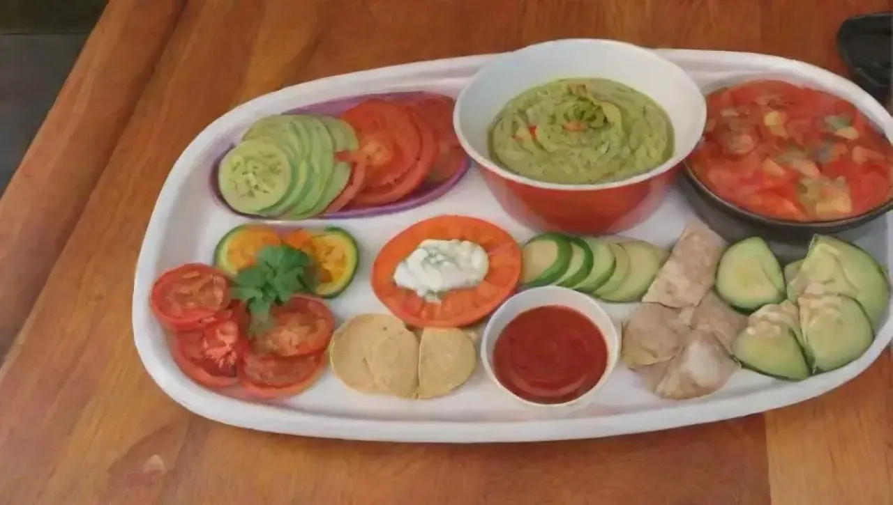 Una mesa colorida y acogedora con salsas, guacamole, hummus, verduras y un ambiente alegre
