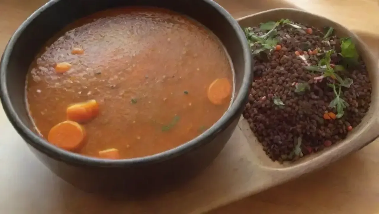 Sopa humeante en un tazón rústico con ingredientes frescos y un ambiente acogedor