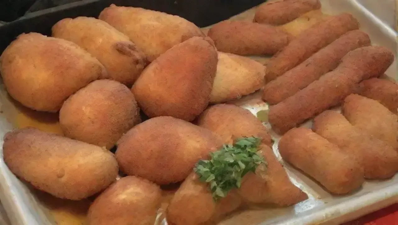Una escena vibrante en la cocina con alitas doradas, especias, risas y amigos disfrutando de una deliciosa comida