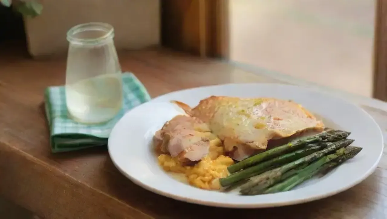 Un acogedor y elegante ambiente de comida con espárragos, pollo, tortilla, hierbas frescas y agua con limón