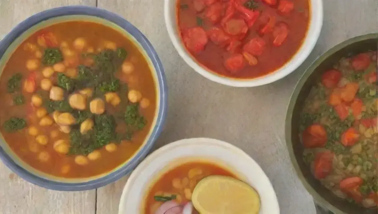 Escena de cocina acogedora con sopa humeante, garbanzos, hierbas frescas y colores vibrantes