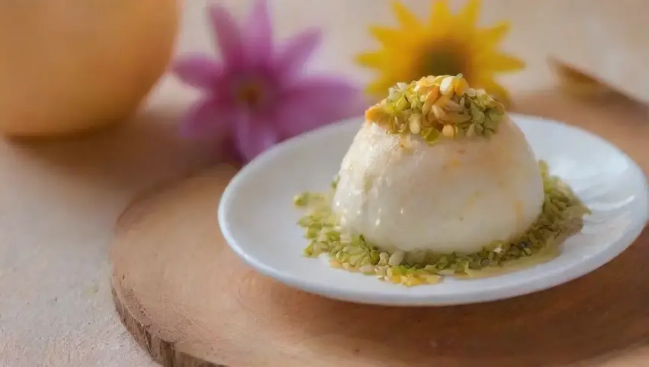 Un elegante postre de mousse de coco con caramelo y flores comestibles en un ambiente cálido y acogedor