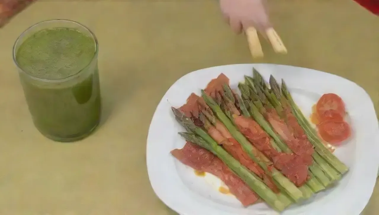 Esparragos verdes con tocino crujiente en un plato blanco, rodeados de un ambiente alegre y colorido