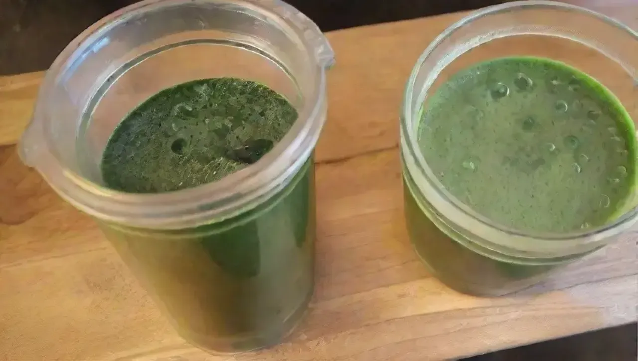 Un colorido batido verde rodeado de ingredientes frescos en una cocina rústica iluminada por la mañana