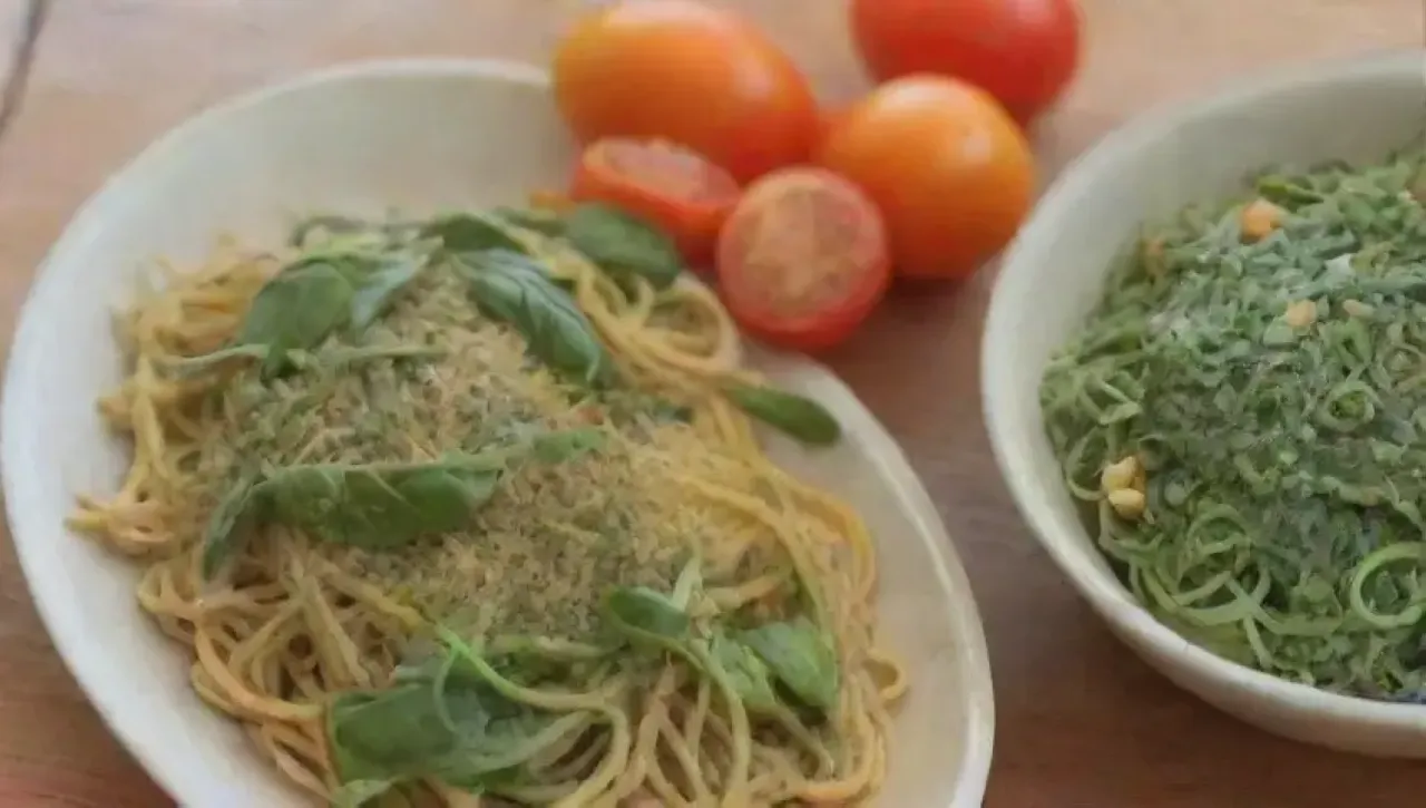 Un acogedor ambiente de cocina con espaguetis al pesto, albahaca fresca y tomates cherry