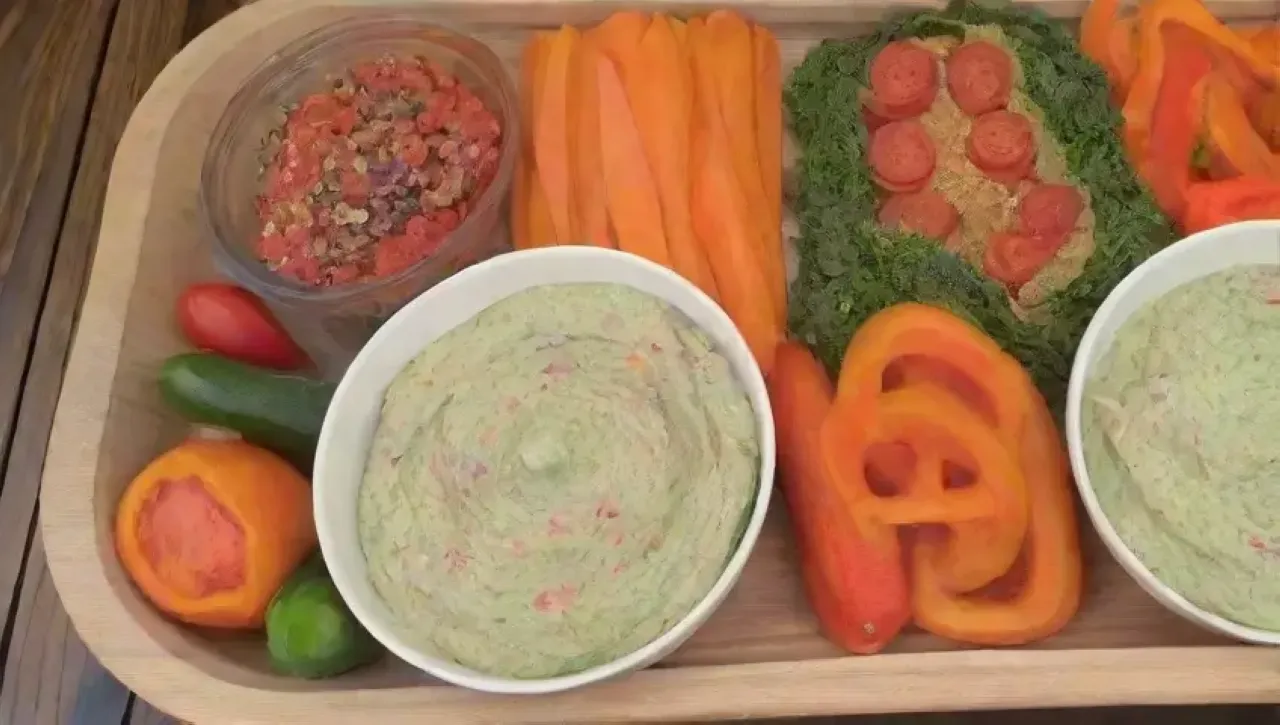 Plato colorido de verduras frescas con hummus, guacamole y salsas