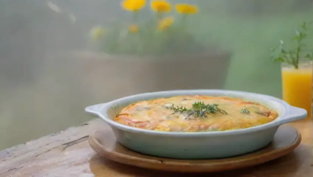 Un delicioso desayuno de omelet amarillo con hierbas frescas y jugo de naranja en un acogedor ambiente de cocina