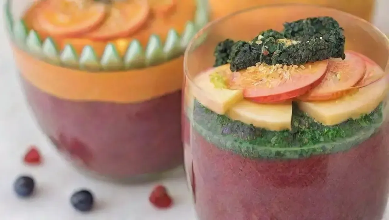 Un batido colorido y nutritivo con kale, zanahorias, arándanos, plátano, chía, leche de almendra, corazones de cáñamo, menta, aguacate, espirulina, nueces, coco, fresas, linaza, agua de coco, acai, cúrcuma, tofu, remolacha, manzana, jengibre, mango, mantequilla de maní y nibs de cacao