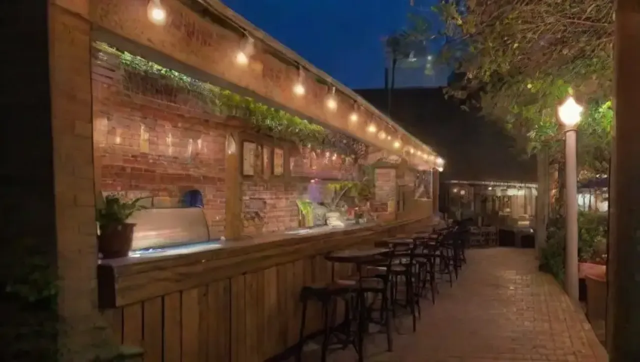 Un ambiente acogedor y vibrante con mesas de madera, luces suaves, arte colorido y detalles únicos