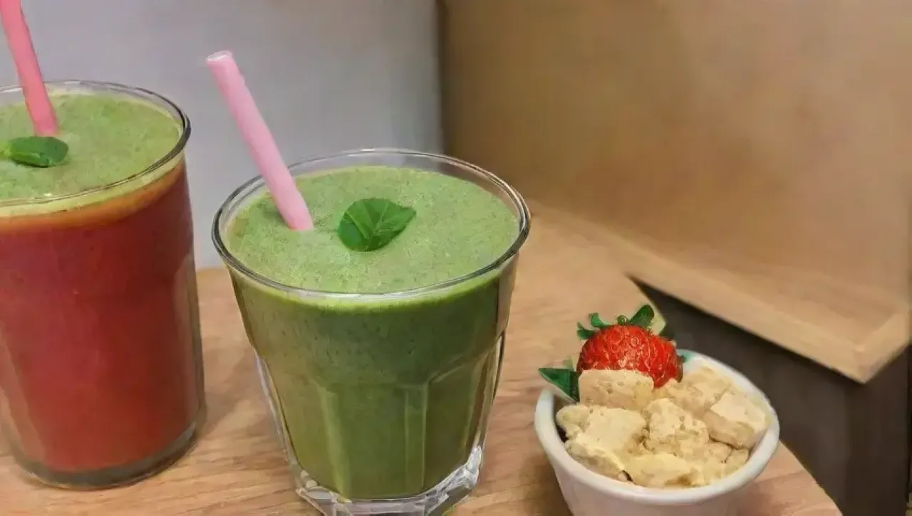 Un colorido batido saludable se prepara en una cocina soleada con frutas frescas y un ambiente alegre