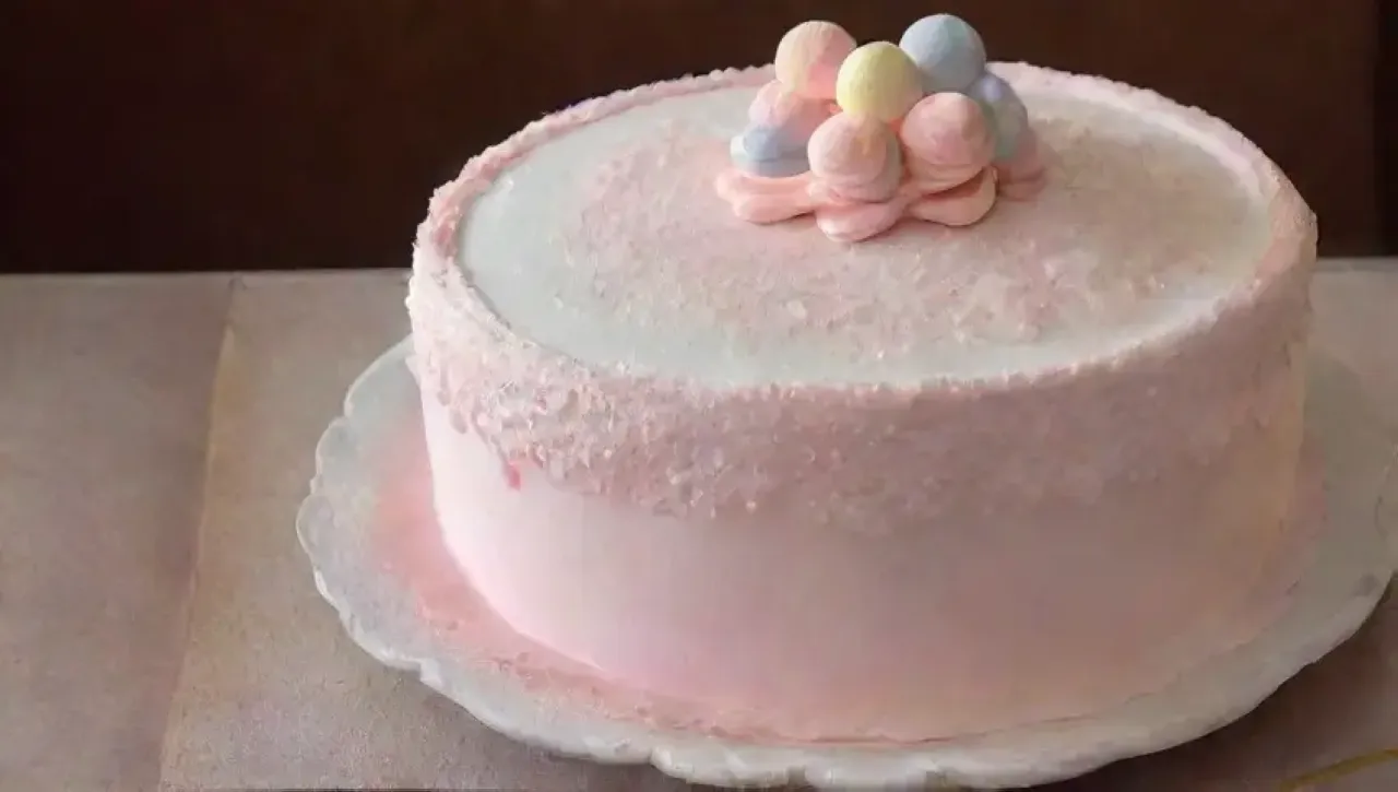 Un pastel colorido decorado con glaseado, flores frescas y un ambiente cálido de cocina