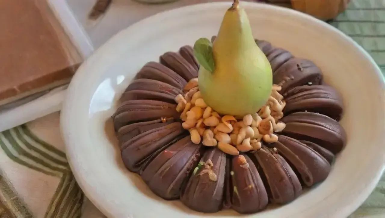 Un delicioso postre de peras con chocolate y nueces en un ambiente acogedor