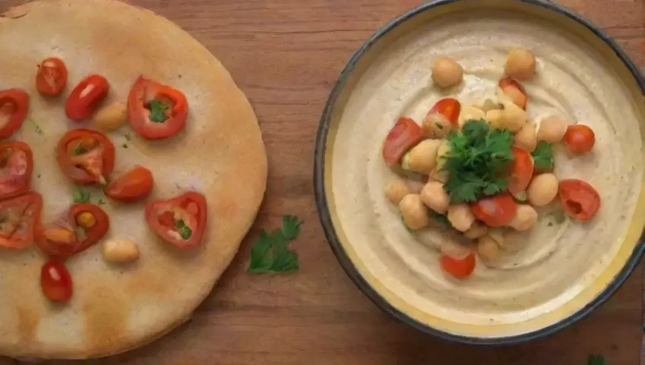 Un festín de hummus cremoso, garbanzos brillantes, perejil fresco y pita crujiente en un ambiente acogedor