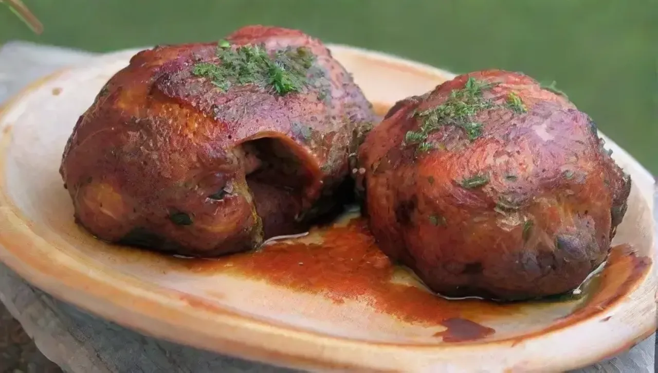 Muslos de pollo dorados y glaseados con BBQ, acompañados de ensalada de col, en un ambiente soleado y festivo