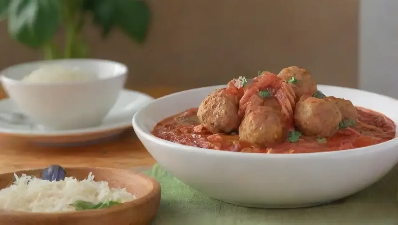 Una acogedora escena familiar con pasta, albóndigas y salsa de tomate en una mesa rústica