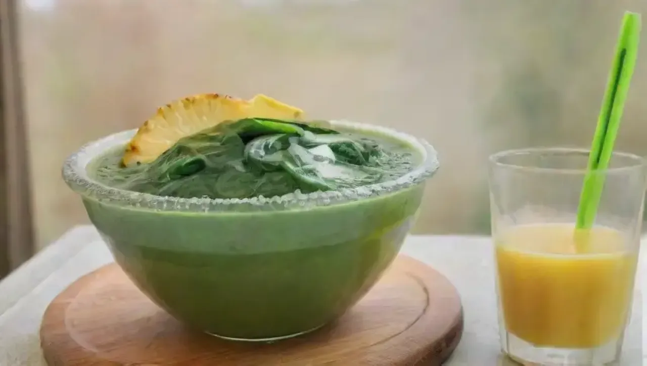 Un colorido batido saludable con espinacas, piña, jengibre y coco en una cocina rústica