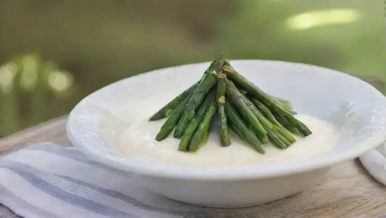 Crema de espárragos elegante en un tazón de porcelana, decorada con cebollino y aceite de oliva, en un ambiente acogedor