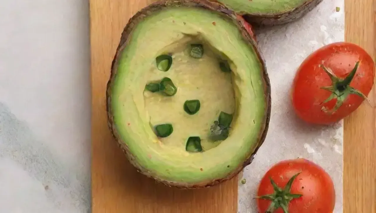 Un delicioso plato de aguacates sobre pan tostado, con tomates, cilantro, aceite de oliva, limón y un refrescante vaso de limonada en una acogedora cocina