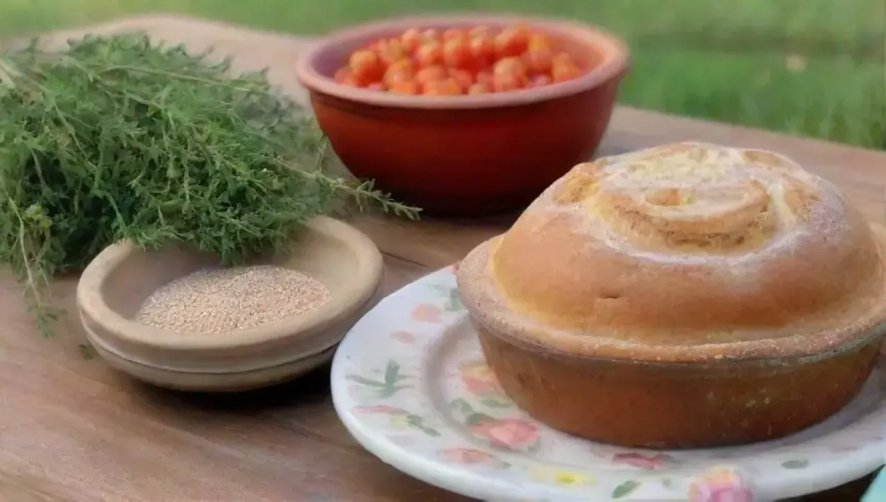 Mesa rústica con pan artesanal, hierbas frescas y tomates, todo en un ambiente acogedor