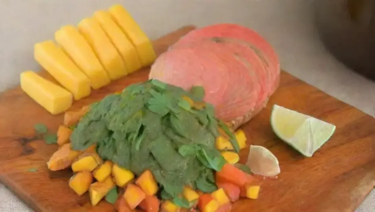Una colorida y fresca salsa de mango acompaña salmón a la parrilla en un ambiente acogedor