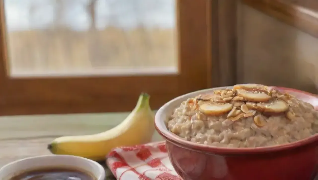 Un desayuno acogedor de avena humeante con frutas, miel y café en una cocina iluminada por la mañana