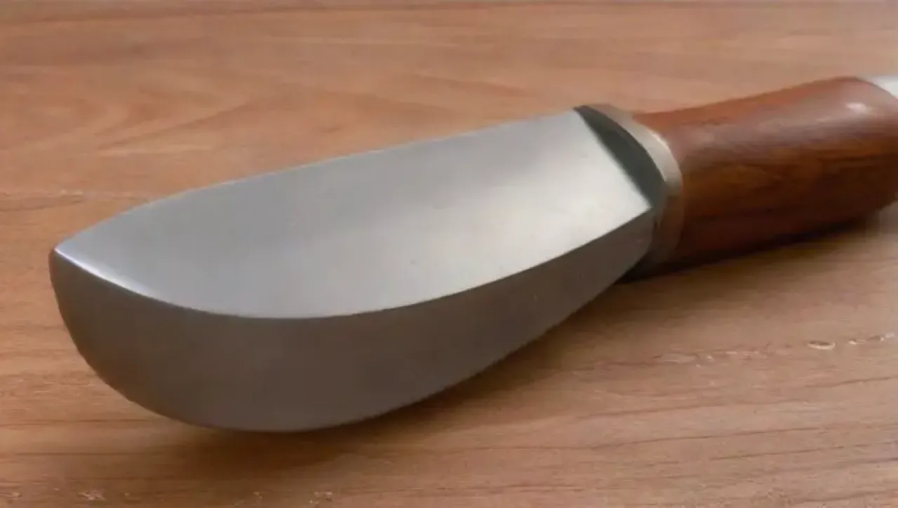 Un cuchillo elegante brilla bajo la luz suave, mostrando su hoja pulida y un mango de madera rica, listo para cortar entre hierbas frescas y un fondo de piedra texturizada