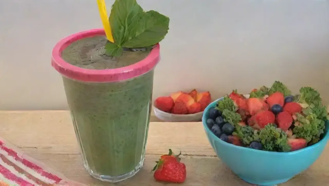 Un colorido smoothie rodeado de frutas frescas en una acogedora cocina