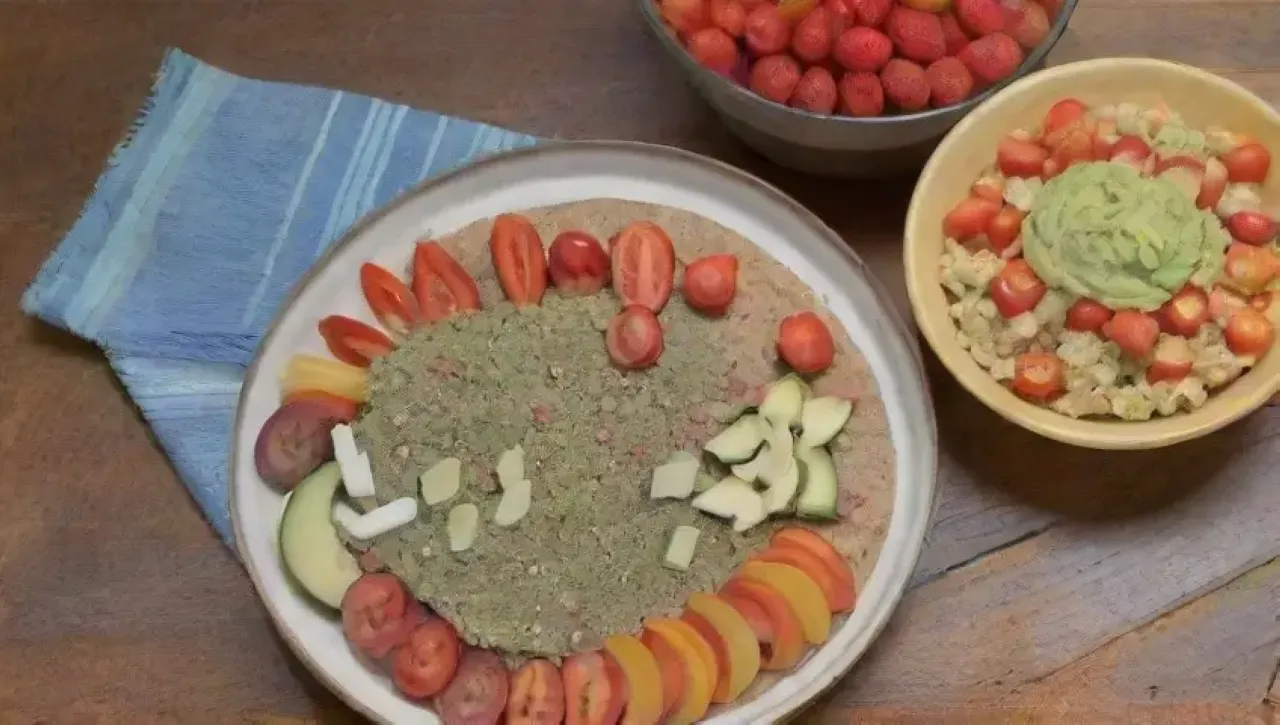 Mesa rústica con snacks coloridos y saludables, incluyendo hummus, ensalada de quinoa, frutas y té de menta